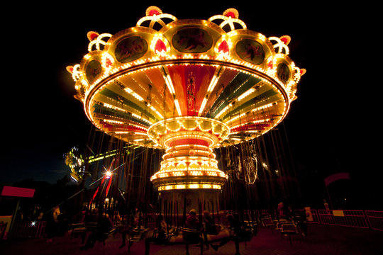 Colorful chain swing carousel in motion at amusement park at night.
