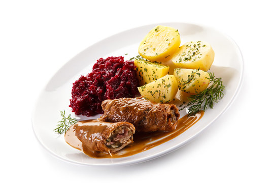 Wrapped pork chops with potatoes and beetroots on white background