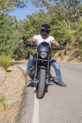Obraz premium Front view of man sitting on parked custom motorcycle on road in mountains. 
