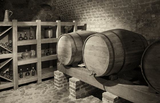 Barrels with a wine in a cellar with a brick wall in background. Black and White Photography. Beautiful vintage.