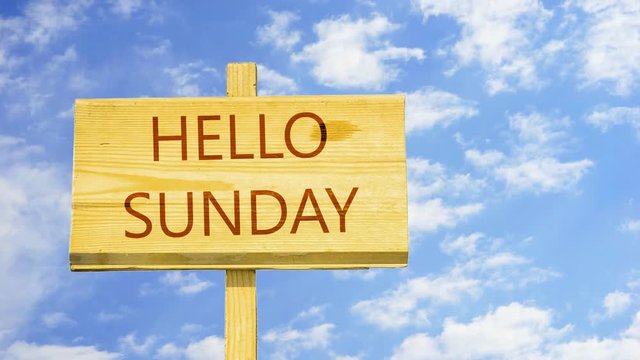 Hello Sunday. Words on a wooden sign against time lapse clouds in the blue sky. 