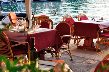 Stoliki restauracyjne nad brzegiem zatoki w Chorwacji. - obrazy, fototapety, plakaty