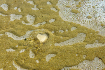Stone in the form of a heart is washed by the sea