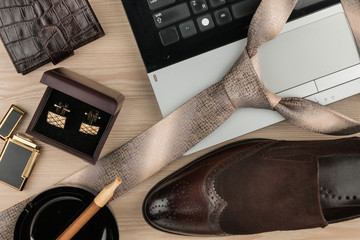 Fashion and business, notebook, shoes, cufflinks, cigar and tie on a wooden table as background.