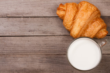 glass of milk with croissants on old wooden background with copy space for your text. Top view