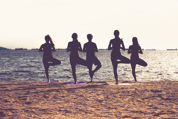 Silhouette of  yoga group of people doing tree pose and namaste with calm relax emotion at beach,Meditation pose,Wellness and Healthy Lifestyle.