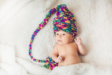 newborn baby in New Year's gnome Cap lays On a white blanket