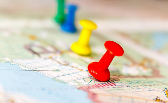 Travel destination points on a map indicated with colorful thumbtacks and shallow depth of field with space for copy.