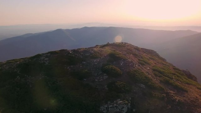 Aerial footage of epic and inspiring landscape of high alp mountains during sunset or twillight with beautiful sun light leaks and beams entering frame, mesmerizing and aweing nature