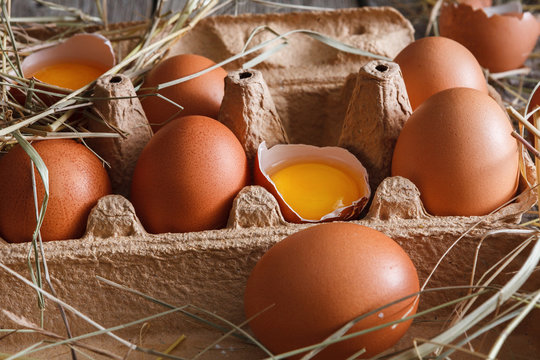 Fresh chicken brown eggs in carton on rustic wood background