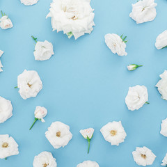 Round frame of white roses flowers on blue background. Flat lay, top view. Floral background.