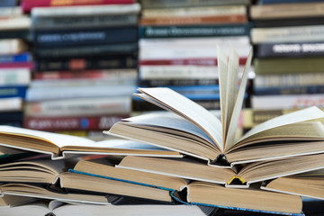 A stack of books with colorful covers. The library or bookstore. Books or textbooks. Education and reading. Open book in the foreground.