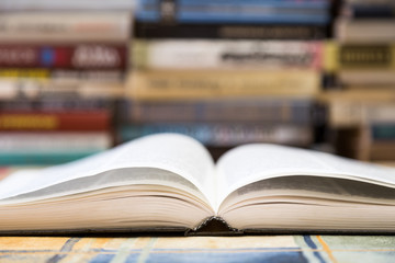 A stack of books with colorful covers. The library or bookstore. Books or textbooks. Education and reading. Open book in the foreground.