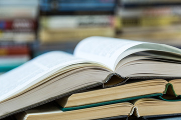 A stack of books with colorful covers. The library or bookstore. Books or textbooks. Education and reading. Open book in the foreground.