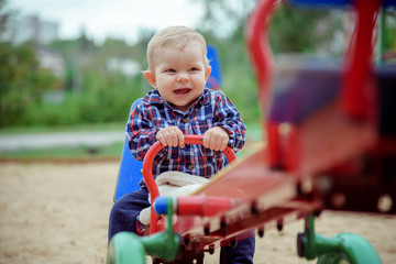 Happy little baby boy playing on the playground in the summer or autumn day