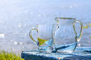Empty jug and a mug are stand on the table by lake