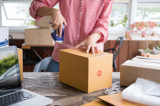 business owner packing cardboard box at workplace. freelance woman seller prepare parcel box of product for deliver to customer.  Online selling, internet marketing, e-commerce, shipping concept