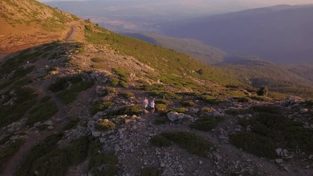 Motivating and inspiring healthy lifestyle drone video of two hikers or climbers exploring nature in national mountain park, walking through rocky ridge during mesmerizing colorful sunset