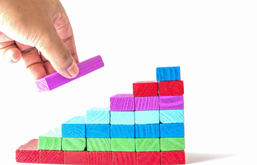 Make success,Concept of building success foundation. Hand put red puzzle wooden blocks in the shape of a staircase