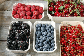 Raspberries, blueberries, blackberries and cherries in carton boxes