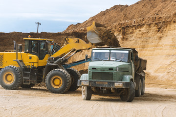 excavator loading sand in dumper truck at sand quarry