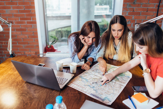 Female office workers planning vacation using map