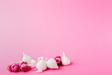White meringues and roses buds at pink background