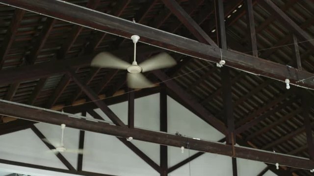Static shot of three ventilators used as air conditioners for cooling the air in industrial building during hot summer days, fans placed on metal with wood ceiling of factory or creative space