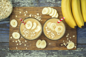 Useful and delicious smoothies. Banana smoothies with oatmeal on a wooden board on a  blue wooden background, top view