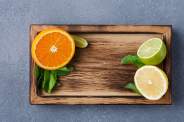 Variety of fresh citrus fruits on wood at gray background