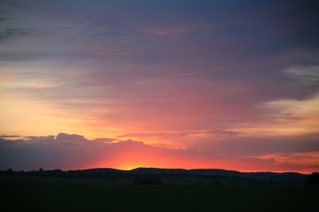 Obraz premium Natural Sunset Sunrise Over Field Or Meadow. Bright Dramatic Sky And Dark Ground. Countryside Landscape Under Scenic Colorful Sky At Sunset Dawn Sunrise. Sun Over Skyline, Horizon. Warm Colours.