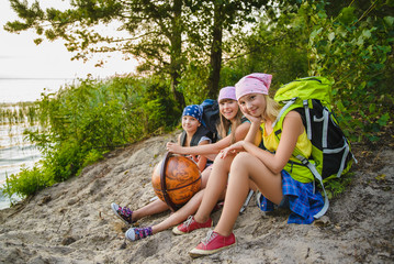 Teenager travelers with backpacks sitting on coast. Wanderlust travel concept