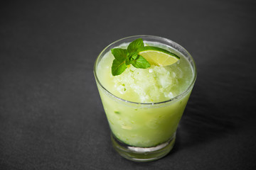 Cocktail juice with lime, mint and ice. Bar drink accessories on black table background.