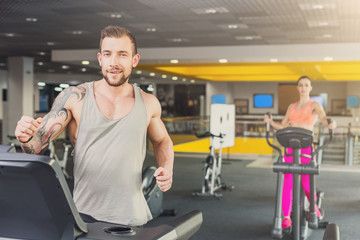 Fototapeta na wymiar Young man in gym run on treadmill
