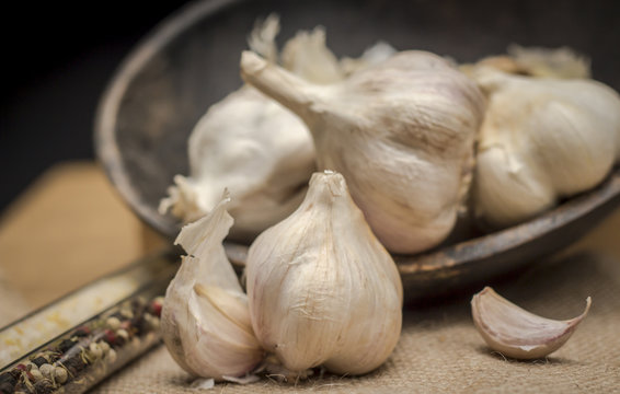 Garlic tubers in rustic wooden bowl on burlap