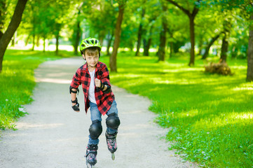 Boy learn to roller skate in summer park. Space for text