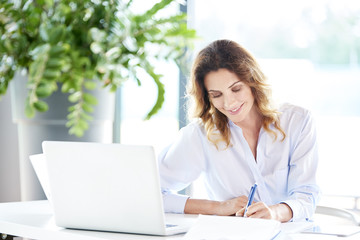 Let's do my business.Portrait of a smiling financial businesswoman working on laptop at the office