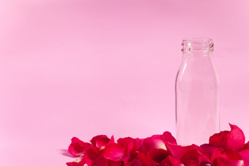 Empty bottle and rose petals On the pink background