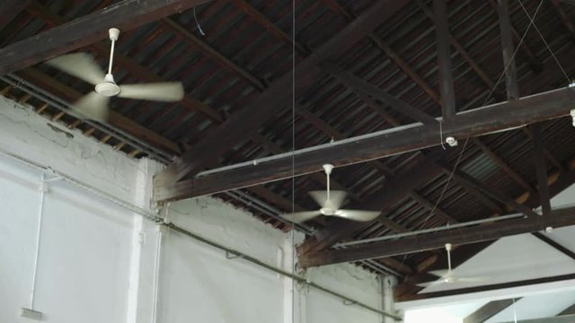 Three air conditioner ventilators or ceiling fans are cooling air and creating wind flow or stream to cool down hot room or industrial production building