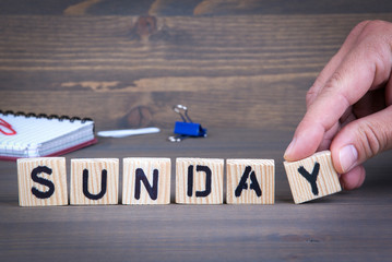 Sunday from wooden letters on wooden background.