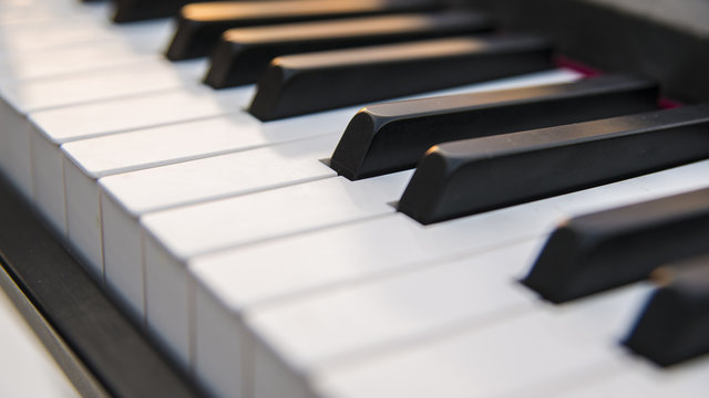 Dettaglio dei tasti di un pianoforte antico ma ristrutturato e rimesso a nuovo. La tastiera è composta da 88 tasti, di colore bianco e nero, sui quali si riflettono i colori caldi del tramonto.