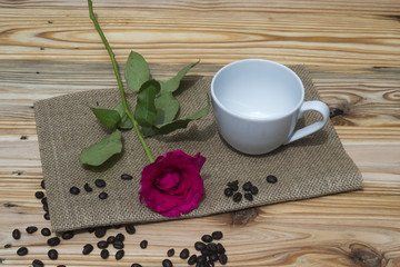 Pink rose coffe cup and coffee beans on wooden table