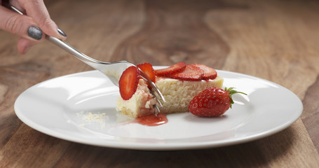 cheesecake with strawberry on plate eaten with fork