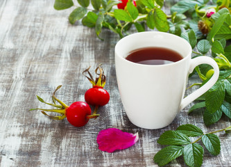 Tea from a dogrose in a mug on a wooden background with fruits