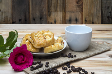 Morning breakfast coffe cup and pink rose on wooden table