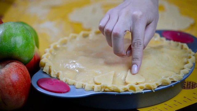 Cooking apple pie, kitchen wooden table, the girl his hands in the frame decorates the cake