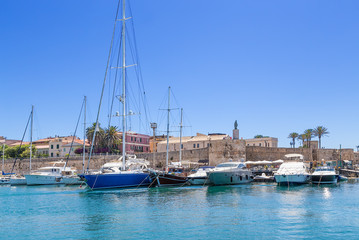 Fototapeta na wymiar Alghero, Sardinia, Italy. Boats and yachts in the port against the walls of the fortress