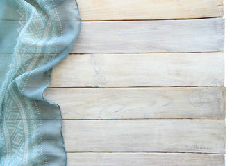 Blue material with ornament and grunge wood board background. Surface of aged white wooden planks and painted shawl fabric, top view, empty place.