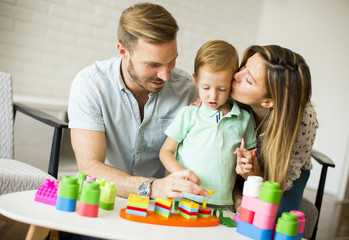Little boy playing toys with mother and father at home
