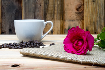 Pink rose coffe cup and coffee beans on wooden table